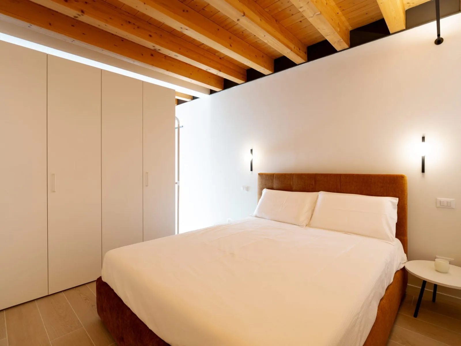 Camera da letto con soffitto in legno e testiera senape monolocale S-02 Ca' Toni Treviso