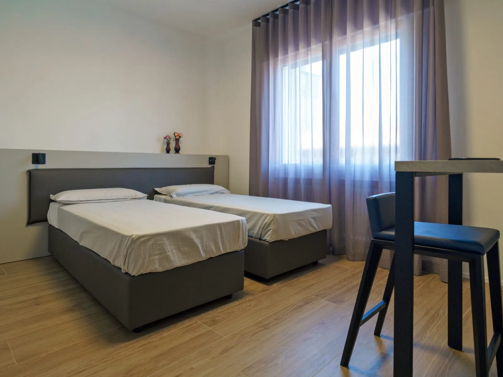 Sleeping area with grey single beds and pink curtains