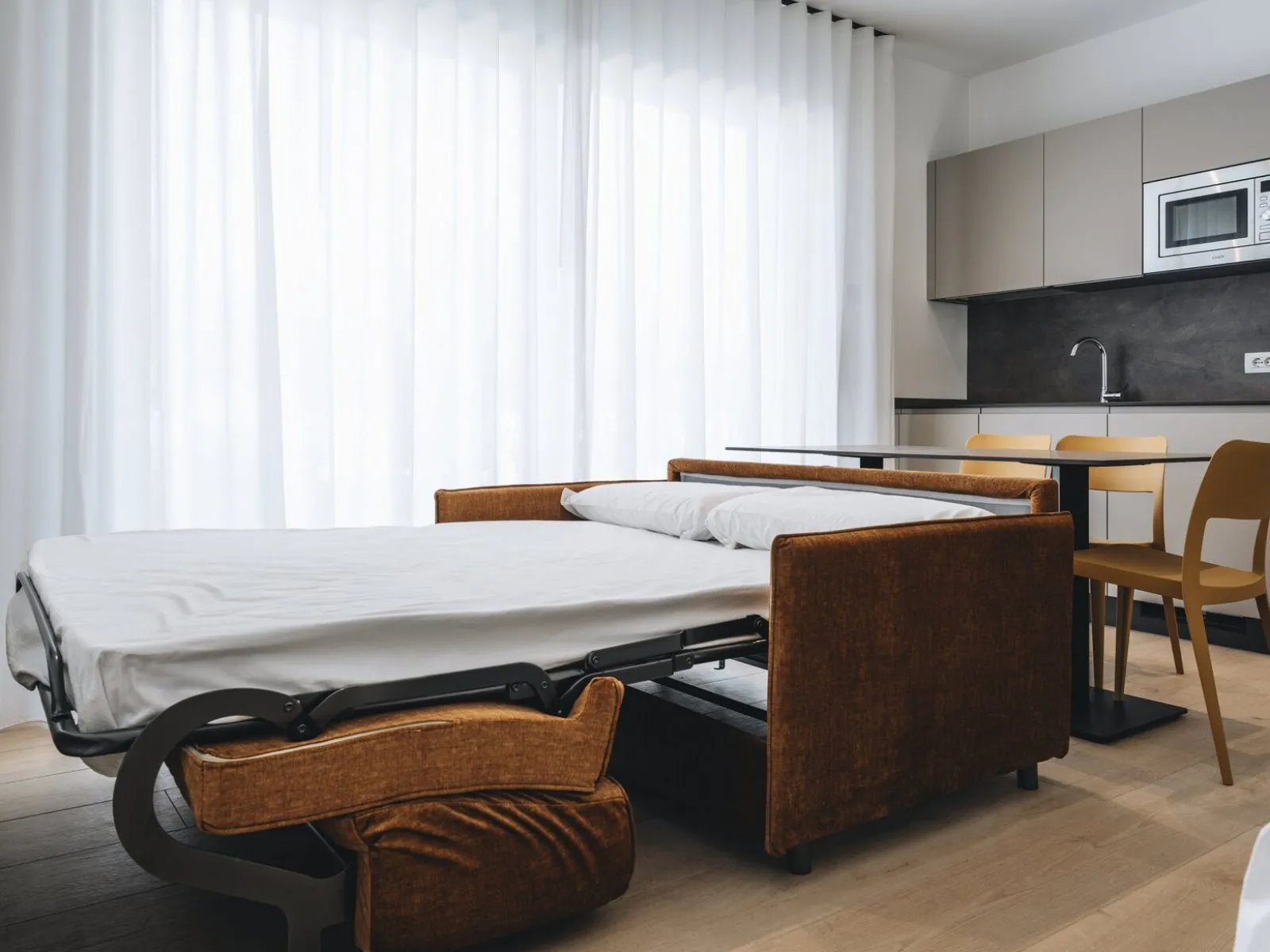 Sofa bed opened in the living area with dining table and kitchen in the background – apartment T-01 Ca' Sette Treviso