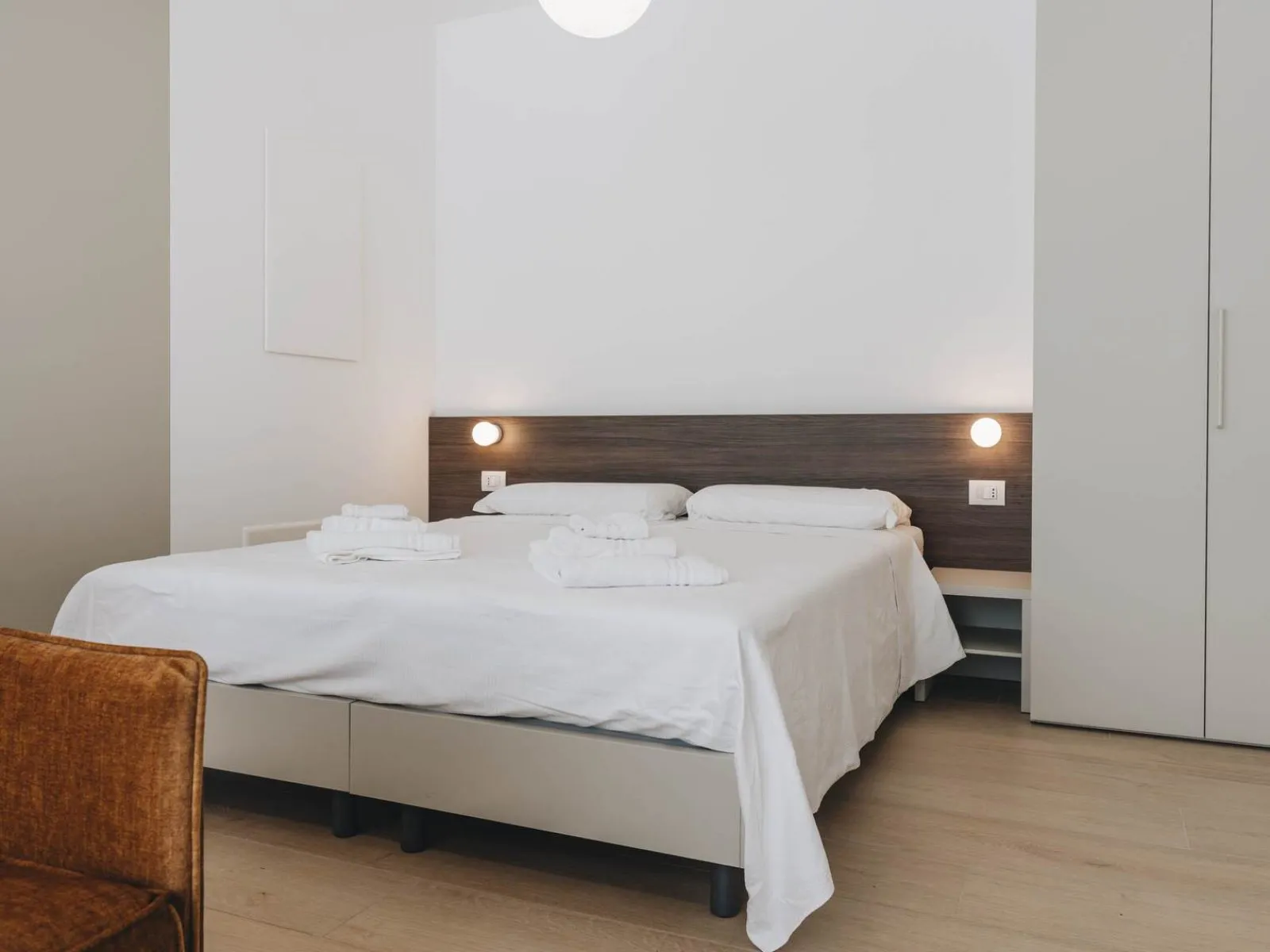 Double bed with dark wood headboard, fresh towels and wardrobe in the background – apartment T-01 Ca' Sette Treviso