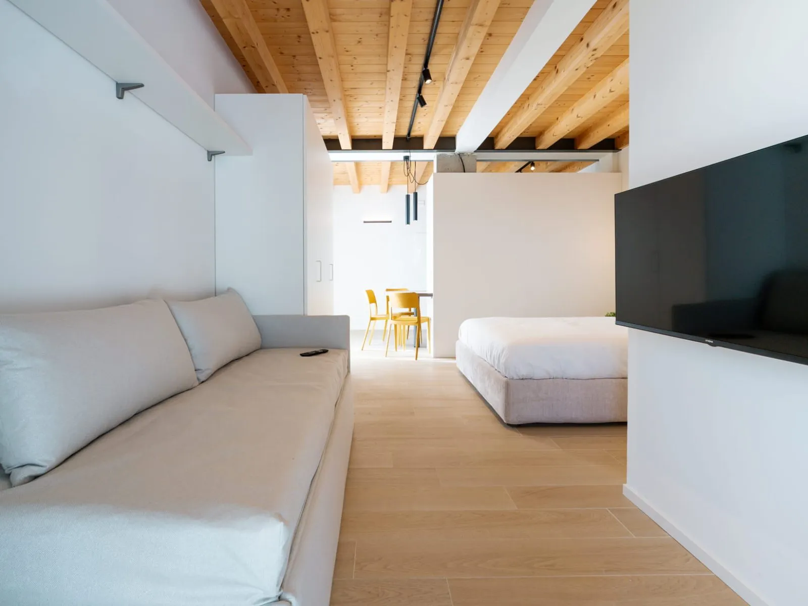 Soggiorno minimalista con divano grigio e TV a parete monolocale S-10 Ca' Toni Treviso