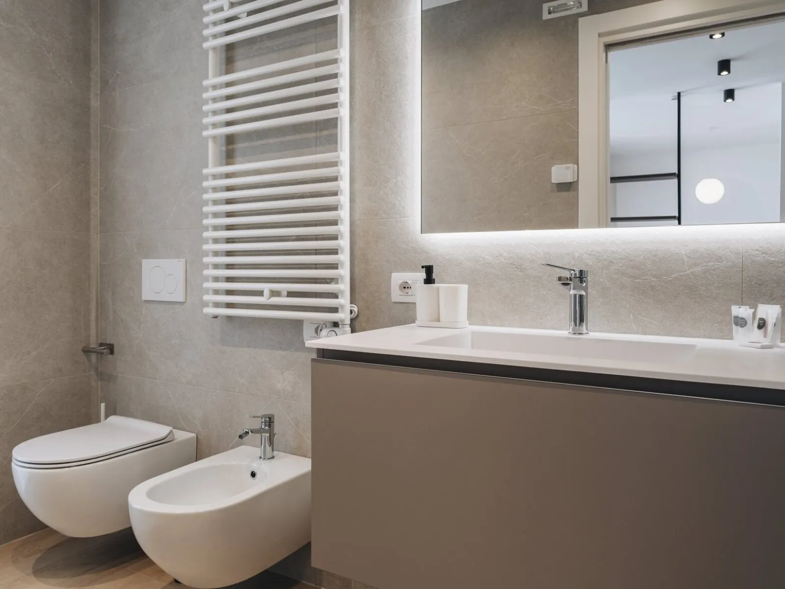 Bathroom with wall-mounted fixtures, washbasin, backlit mirror and heated towel rail – apartment T-02 Ca' Sette Treviso