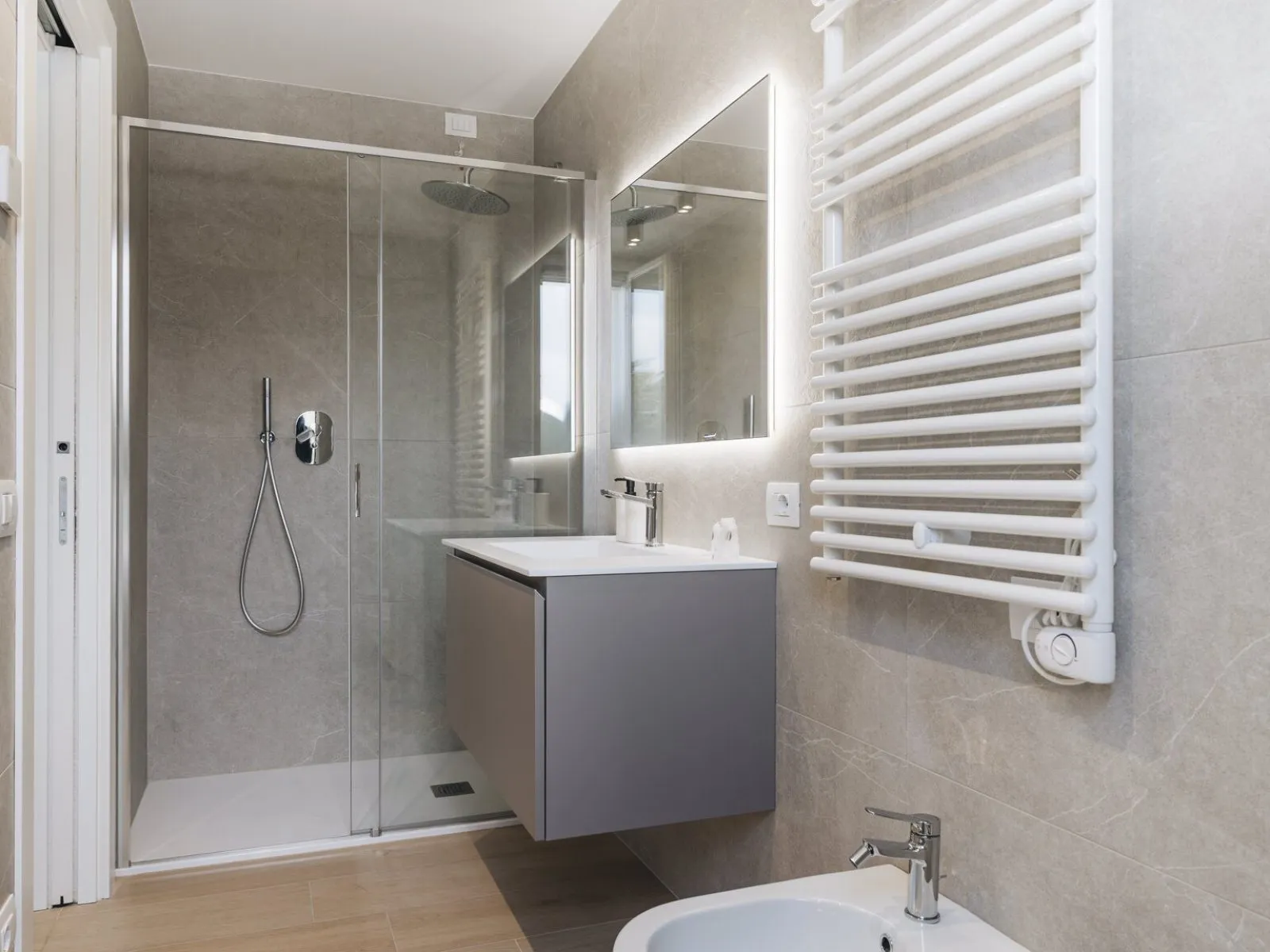 Cucina lineare con pensili bianchi, piano scuro, microonde integrato e pannello a effetto cemento – appartamento T-03 Ca' Sette Treviso