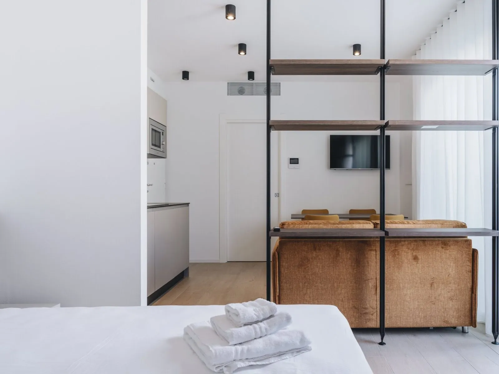 Double bed with dark wood headboard, fresh towels and white bedside table – apartment T-03 Ca' Sette Treviso