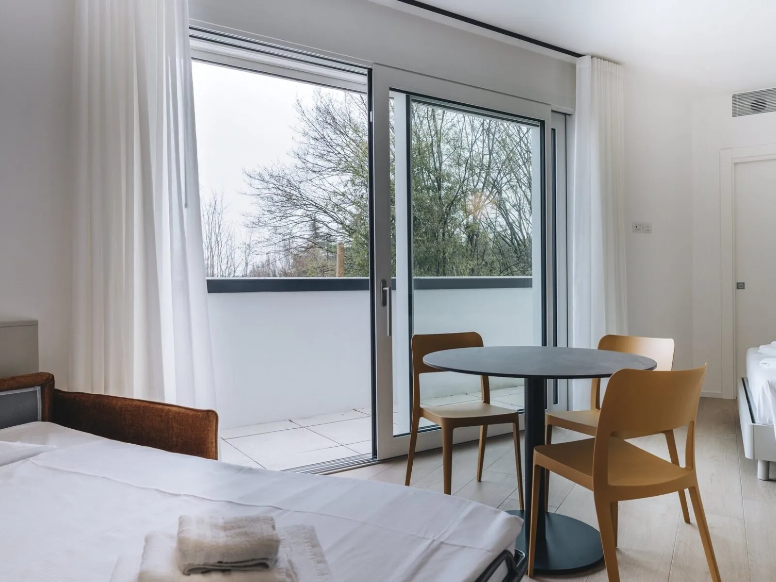 Sofa bed opened with kitchen and concrete-effect splashback in the background – apartment T-04 Ca' Sette Treviso