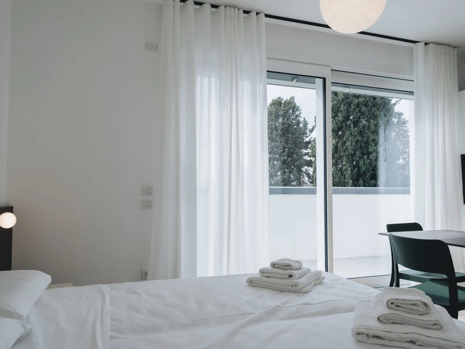 Zona notte con letto matrimoniale, asciugamani e accesso diretto alla terrazza con vista sul verde – appartamento T-07 Ca' Sette Treviso